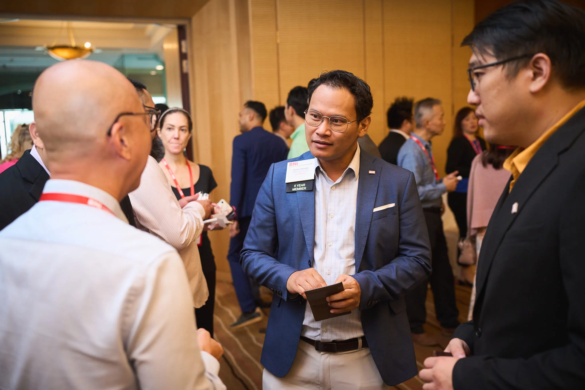 Zai networking at a BNI event with his 5-year member badge